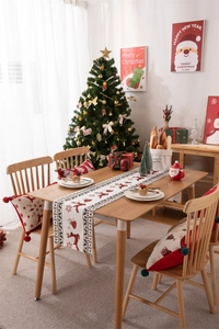 Christmas table runner and pillows with reindeer and tree patterns in holiday dining setting
