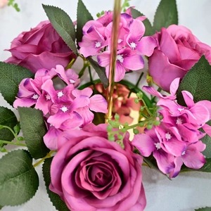 Close-up of purple silk roses and hydrangeas with green leaves on candle ring decor