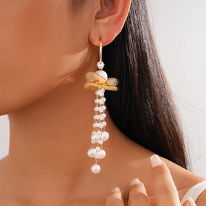 Detail of gold floral leaf earrings with zircon accents and long pearl tassels