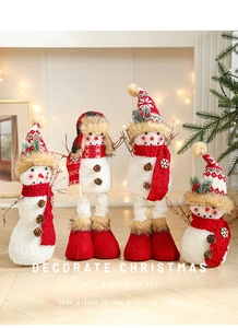 Detail of four festive plush snowmen with knit hats and pinecones in a cozy holiday setting
