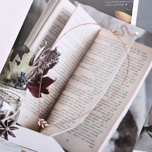 Detailed view of rose gold leaf pendant with diamonds on a vintage book background