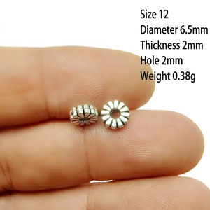 Detail of 6.5mm daisy silver spacer beads showing precise petal texture and dimensions