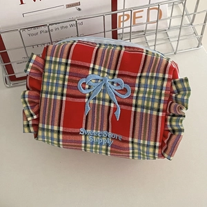 Detail der rot-grünen Karo-Kosmetiktasche mit blauer Schleifenstickerei und Rüschenrand
