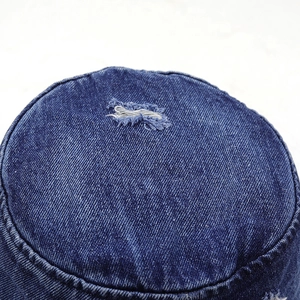 Détail du haut vieilli d'un chapeau bob en jean bleu marine avec fils effilochés blancs