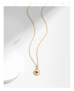 Detailed macro view of S925 sterling silver gold necklace with red gemstone eye pendant