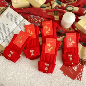 Detail of red cotton New Year socks featuring cute bear embroidery and gift packaging
