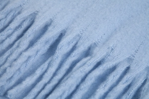 Macro shot of light blue mohair knit scarf showing striped fluffy texture and soft wool material