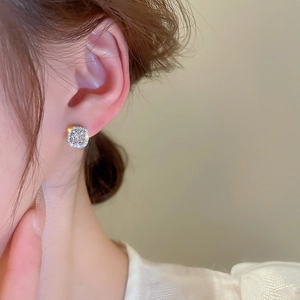 Macro shot of square halo zircon stud earrings on model's ear showing silver texture