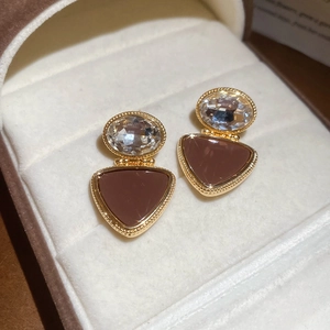 Macro view of gold-plated triangle earrings with brown resin and clear crystals