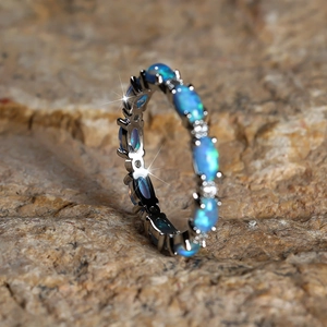 Exquisite silver eternity ring featuring vibrant blue opal stones set on a warm rocky surface