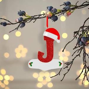 Letter J Christmas tree ornament with glitter finish and a red Santa hat on a branch