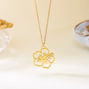 Macro detail of a 18K gold-plated hollow hibiscus flower pendant on a polished O-chain