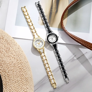 Detail view of gold and silver quartz watches with steel bands on marble surface