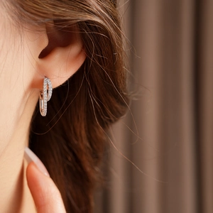Close-up of a silver double hoop earring with cubic zirconia on a model's ear