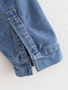 Close-up of sleeve cuff on dark blue denim jacket with orange contrast stitching details