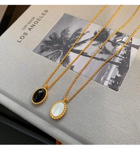 Detailed close-up of retro gold-plated necklaces with black onyx and white shell pendants