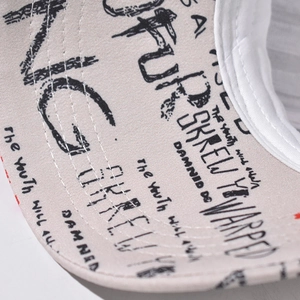 Detailed close-up of beige graffiti baseball cap brim with fine double-row stitching