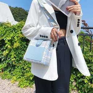 Blue tweed and leather crossbody bucket bag with wide patterned strap on model
