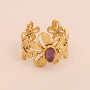 Detail of vintage golden flower ring with oval purple gemstone and hollowed design