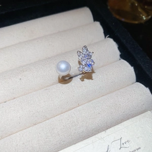 Close-up of bow ring with zircon and pearl on beige velvet in a black jewelry box