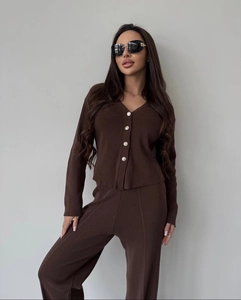 Detail of V-neck knit cardigan with gold buttons and high-waist wide-leg pants