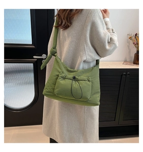 Macro shot of green quilted nylon shoulder bag with drawstring pocket and knotted strap
