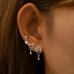 Close-up of S925 silver stud earrings with pink heart and crown charms on model