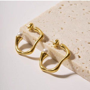 Close-up of irregular 18k gold earrings with pearls on a natural stone base