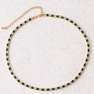 Detail of gold tennis necklace with alternating green and white cubic zirconia stones