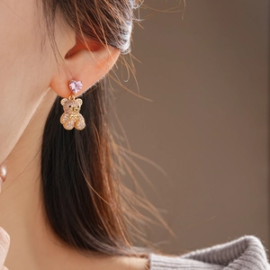 Gros plan d'une boucle d'oreille ours avec zircon cœur rose et strass brillants sur l'oreille