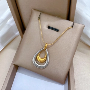 Macro shot of gold and silver double-layered water drop pendants on a gold snake chain