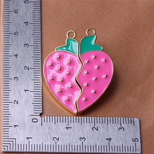 Detailed size measurement of a pink strawberry heart-shaped pendant with a metal ruler