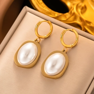 Elegant gold oval pearl earrings on beige velvet display, minimalist luxury style