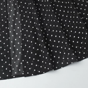 Close-up of black and white polka dot chiffon fabric with smooth stitching details