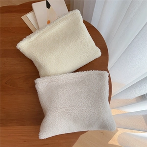 Detailed view of soft off-white lamb wool cosmetic bag on a wooden table setup