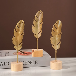 Three golden metal ginkgo leaf ornaments on round wooden bases for modern home decor