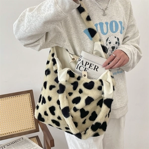 Close-up of plush tote bag showing soft ivory faux fur with black heart pattern details