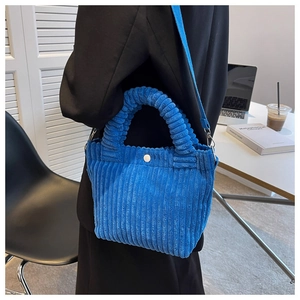 Detailed shot of a blue corduroy bucket bag with vertical texture and white button closure