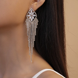 Close-up of luxury zircon flower earrings with long shimmering tassels on a model