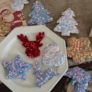 Assorted Christmas sequins shaped as trees and reindeer on a white ceramic plate