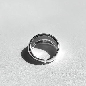 Minimalist polished silver adjustable open ring with smooth metallic finish on grey background