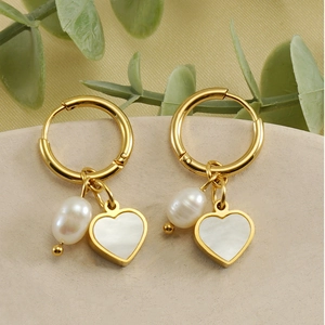 Détail de boucles d'oreilles en or 18K avec pendentifs cœur et perles ovales blanches