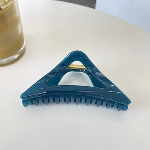 Detail of 12cm dark teal triangular hair claw clip with golden spring and translucent resin