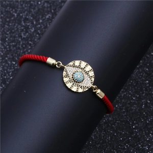 Adjustable red woven cord bracelet with gold-tone cubic zirconia evil eye charm