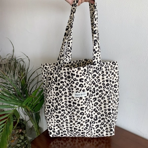Detail of leopard print canvas tote bag with Korean label on white background