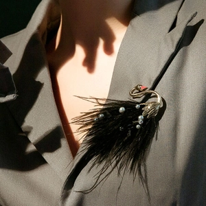 Elegant black feather swan brooch with white pearls pinned on a grey suit lapel