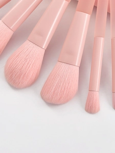 Macro view of peach pink makeup brushes with soft synthetic bristles and matte handles