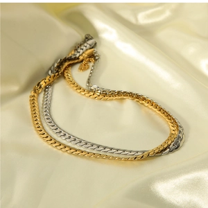 Detailed view of gold and silver flat snake chains on elegant champagne silk fabric