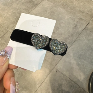 Dettaglio del fermaglio per capelli in velluto nero con doppi cuori di strass lucidi