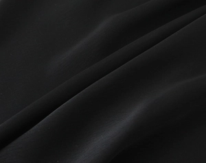 Detail shot of black satin fabric showing premium matte texture and soft fluid drapes